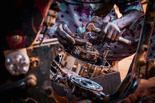 Mechanic focused on assembling motorcycle engine parts in a workshop.