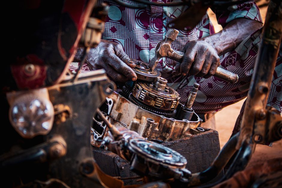 Mechanic focused on assembling motorcycle engine parts in a workshop.