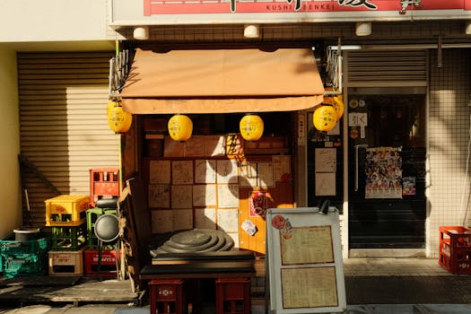 A cozy Japanese eatery with yellow lanterns and signage on a sunny day.