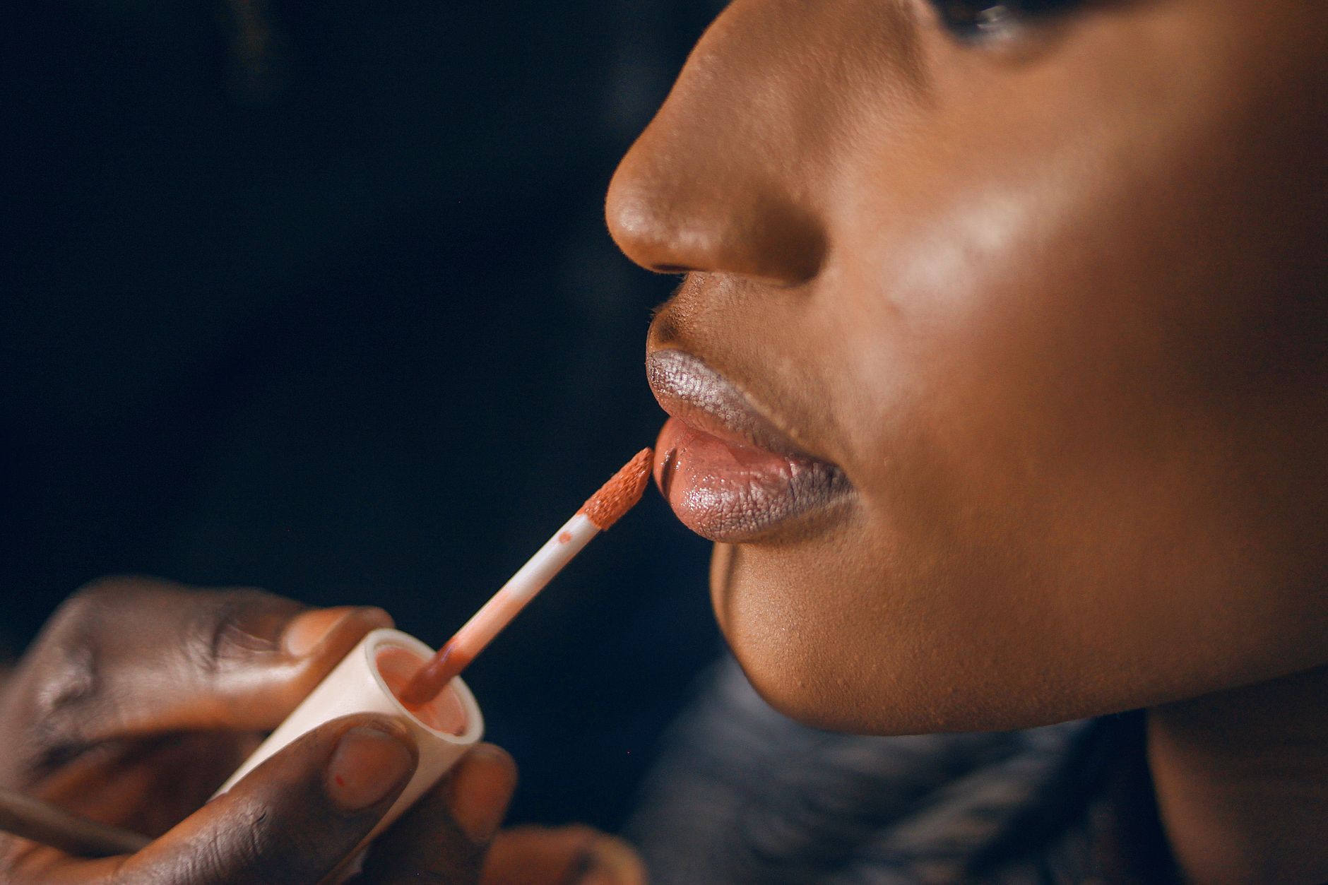 A close-up of glossy lipstick being applied, illustrating the soft-focus, cushioned finish beauty brands now chase in lip contour products.