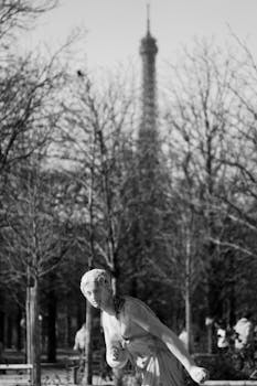 Monochrome image of a statue in a Paris park with Eiffel Tower in the backdrop.