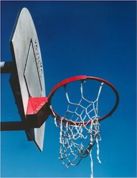 A basketball hoop with a net against a clear blue sky, symbolizing sports and outdoor activity.