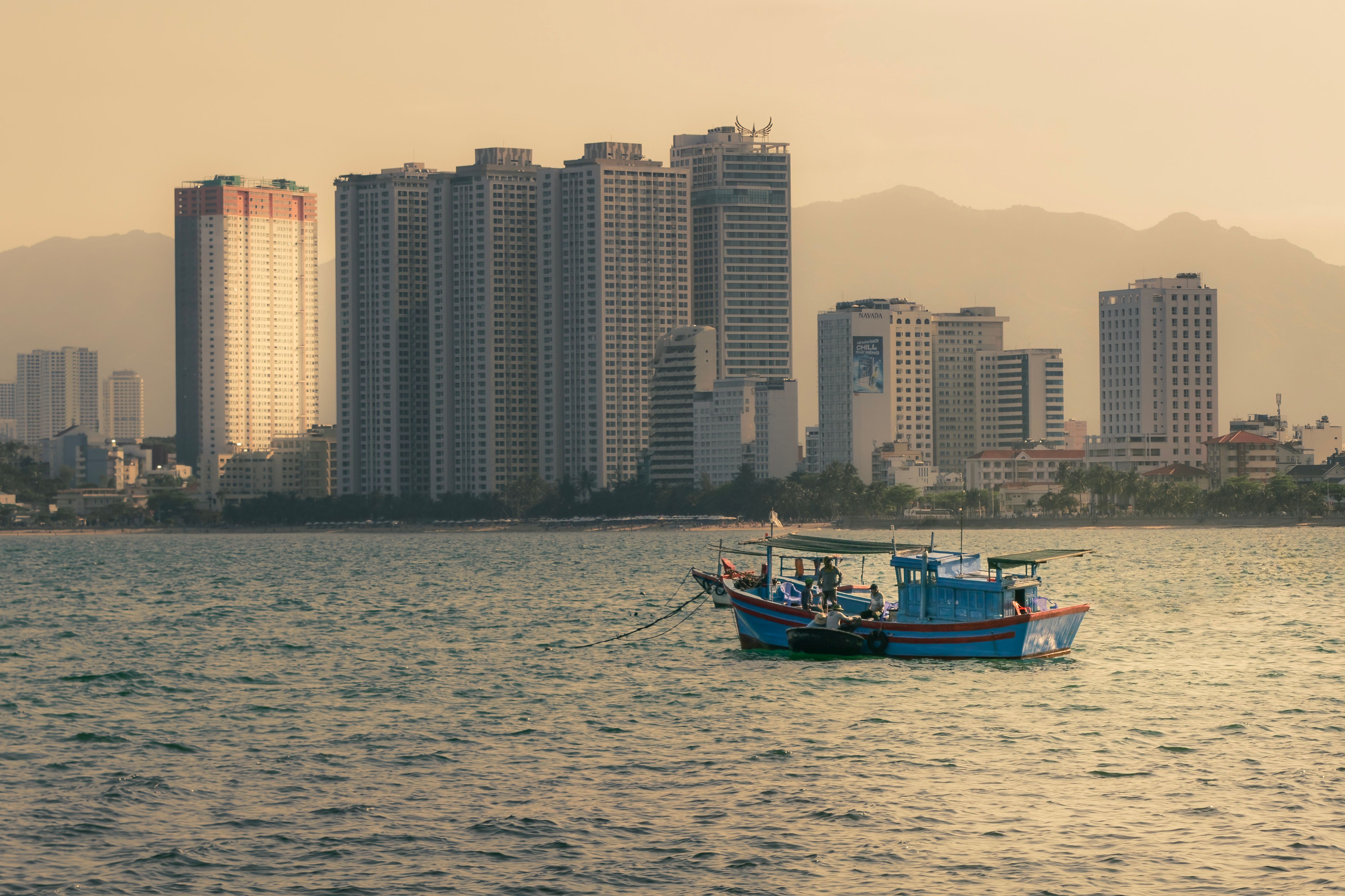 Explore the serene coastal skyline of Nha Trang with boats floating in the calm sea.
