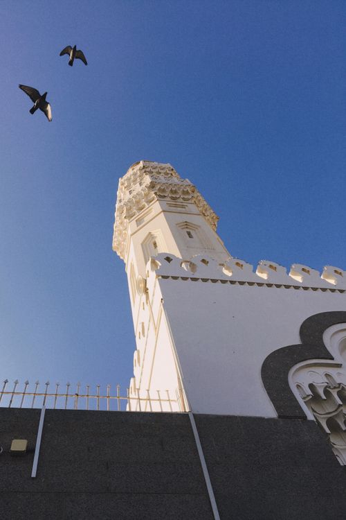 Free A white architectural tower with birds and a clear blue sky background. Stock Photo