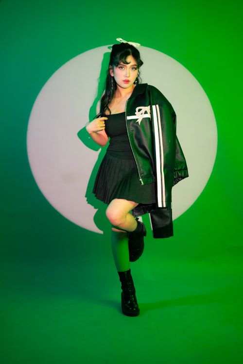 Free Young woman poses in stylish outfit with green lighting background. Stock Photo