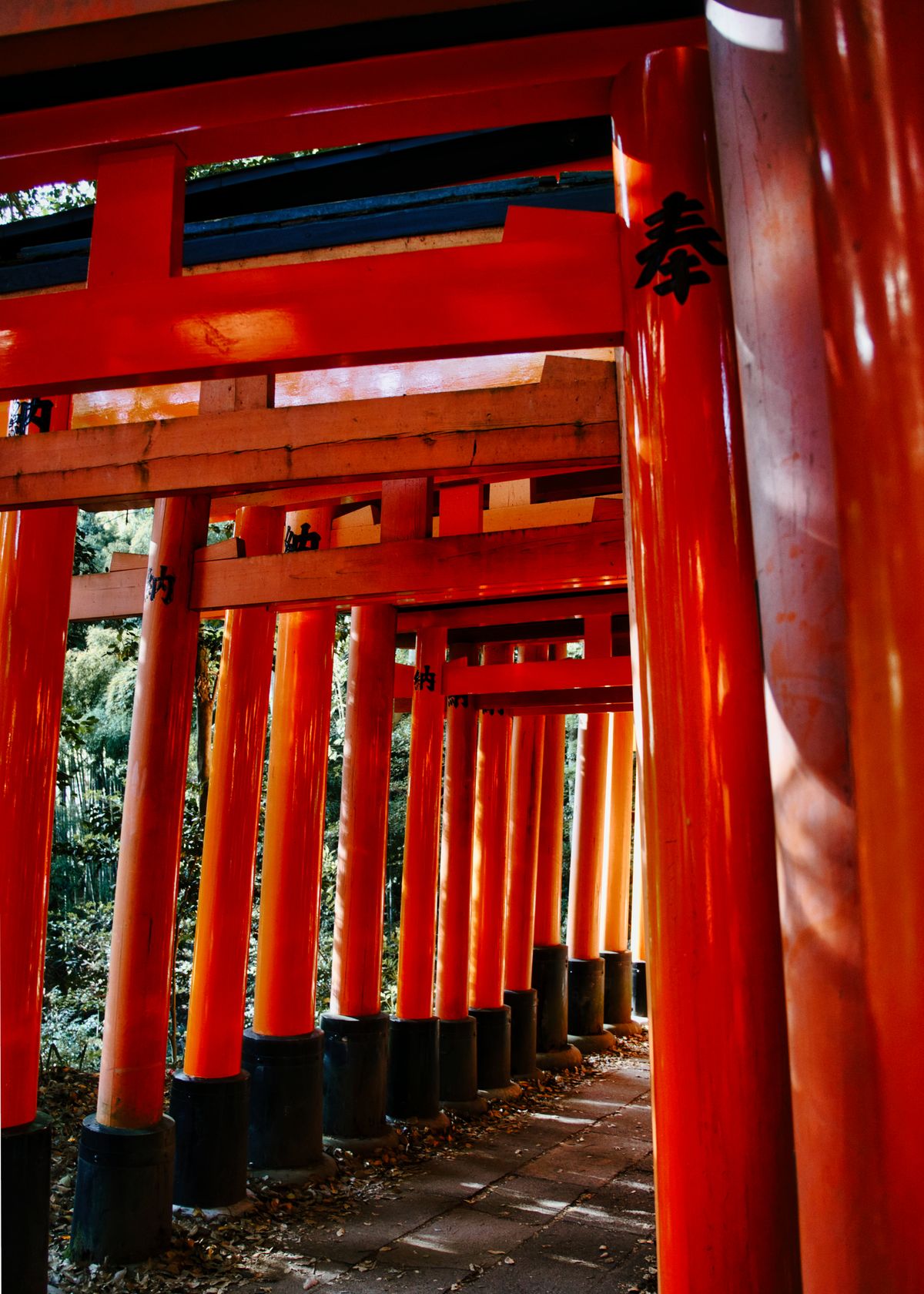 Stone fox kitsune statue at Fushimi Inari Taisha shrine with vermilion torii gates in background