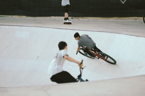 Free Young BMX cyclists performing tricks and stunts in an outdoor skate park bowl. Stock Photo
