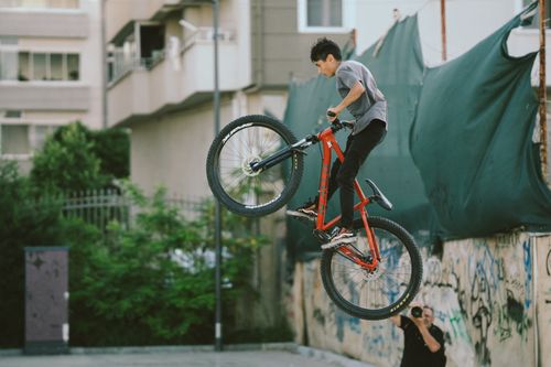 Free A biker performs an impressive stunt with a red mountain bike in a graffiti-filled urban environment. Stock Photo