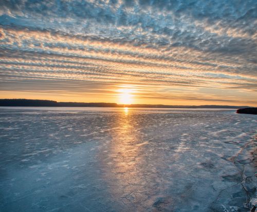 Free Beautiful sunset over a frozen lake in Pepin, Wisconsin, showcasing ice reflections and dramatic clouds. Stock Photo