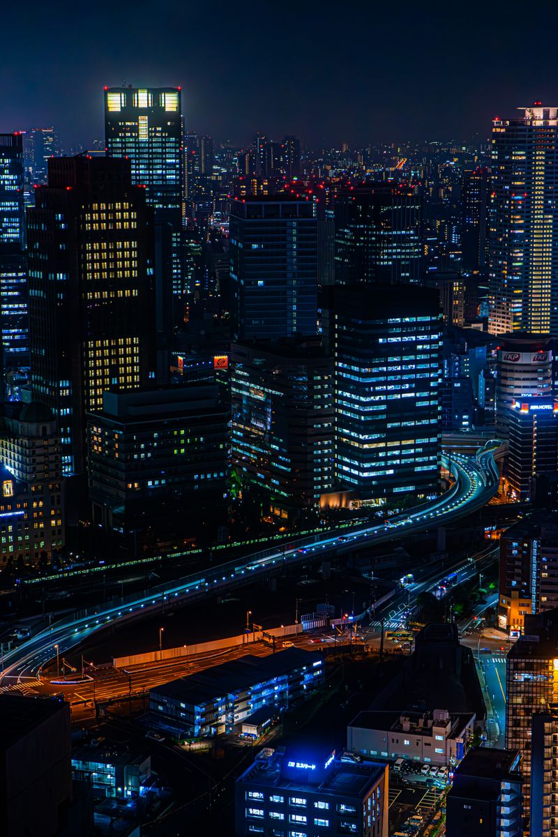 A stunning aerial view of a bustling urban skyline at night with glowing skyscrapers and city lights.