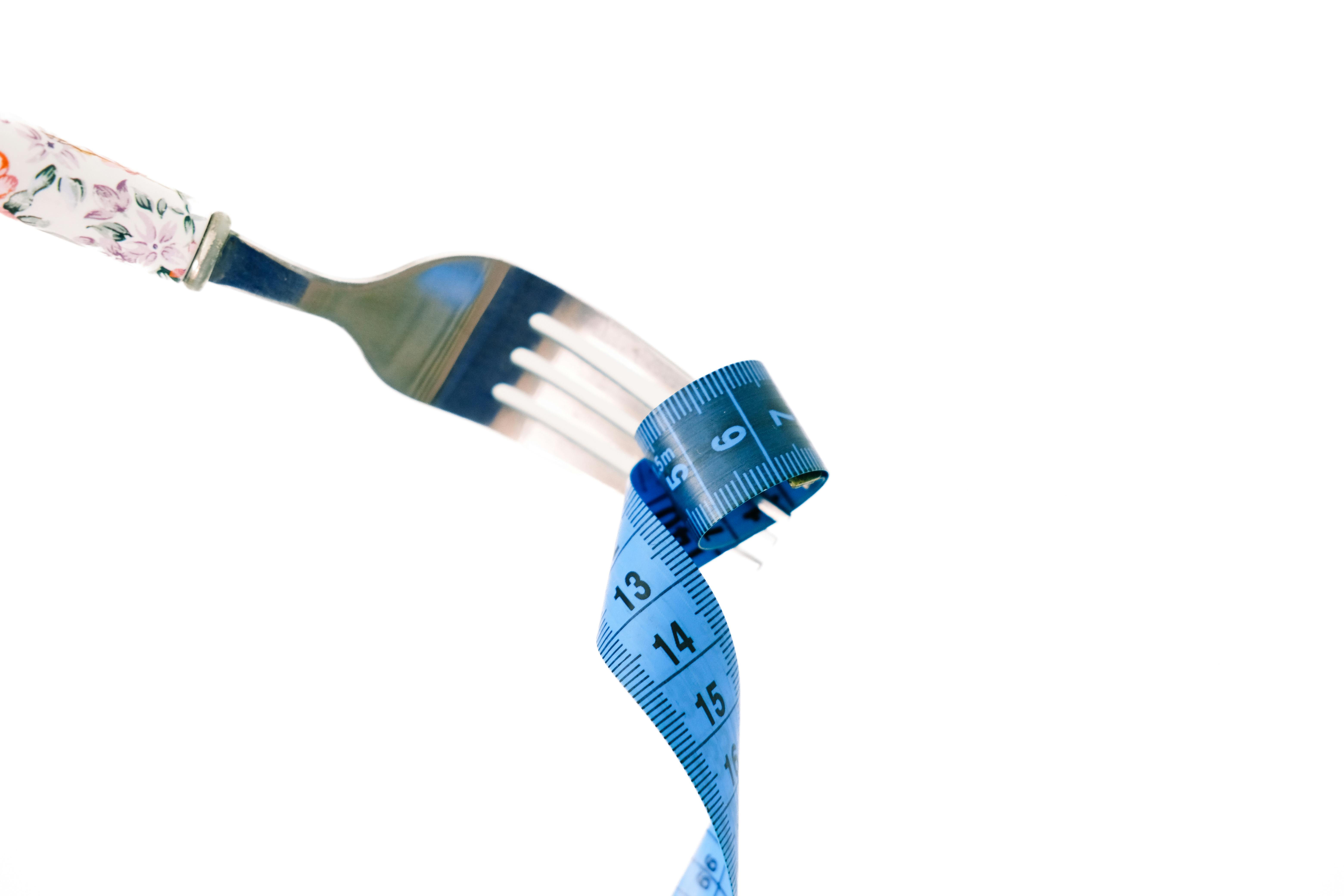 Free A fork twirls a blue measuring tape, symbolizing weight management and health. Stock Photo