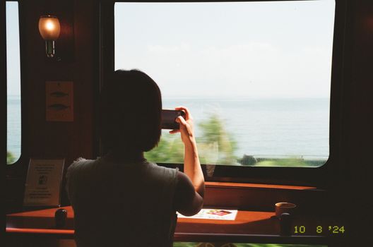 A traveler photographs scenic ocean views from a train window in Japan.