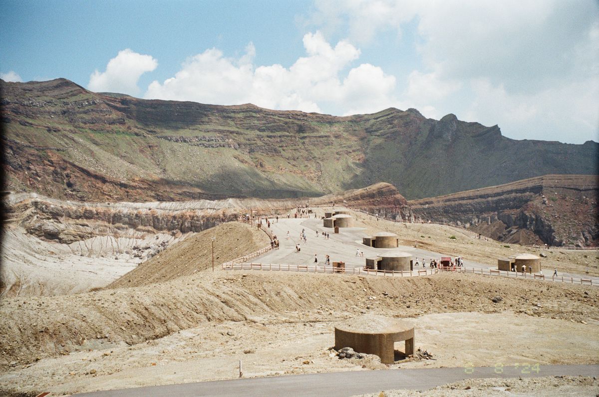 Tourists at the rim of Mount Aso's Nakadake crater — the world's largest active volcanic caldera, accessible year-round when sulphur levels allow
