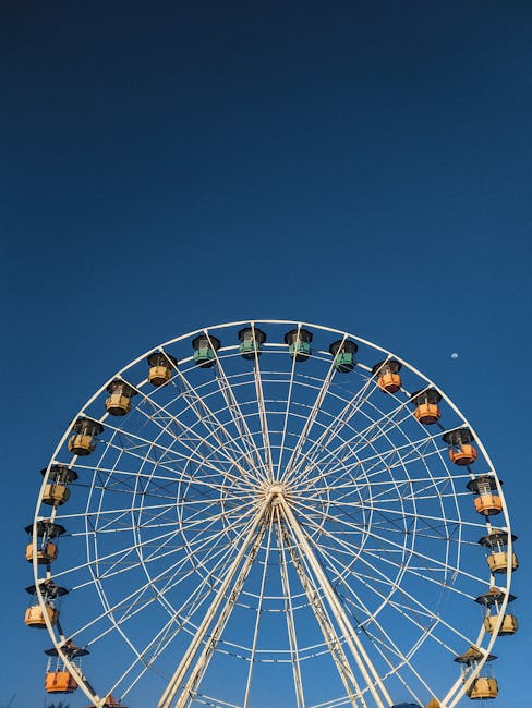 A beautiful Ferris wheel captured from a low angle, highlighted against a clear blue sky.