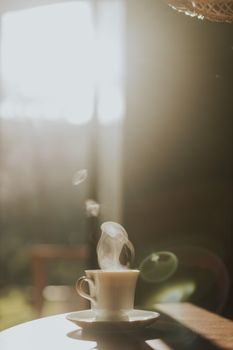 A warm, steaming cup of coffee on a table in a sunlit cafe, evoking a cozy atmosphere.