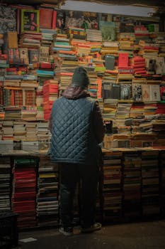 A person views a massive collection of books at a night market bookstall.