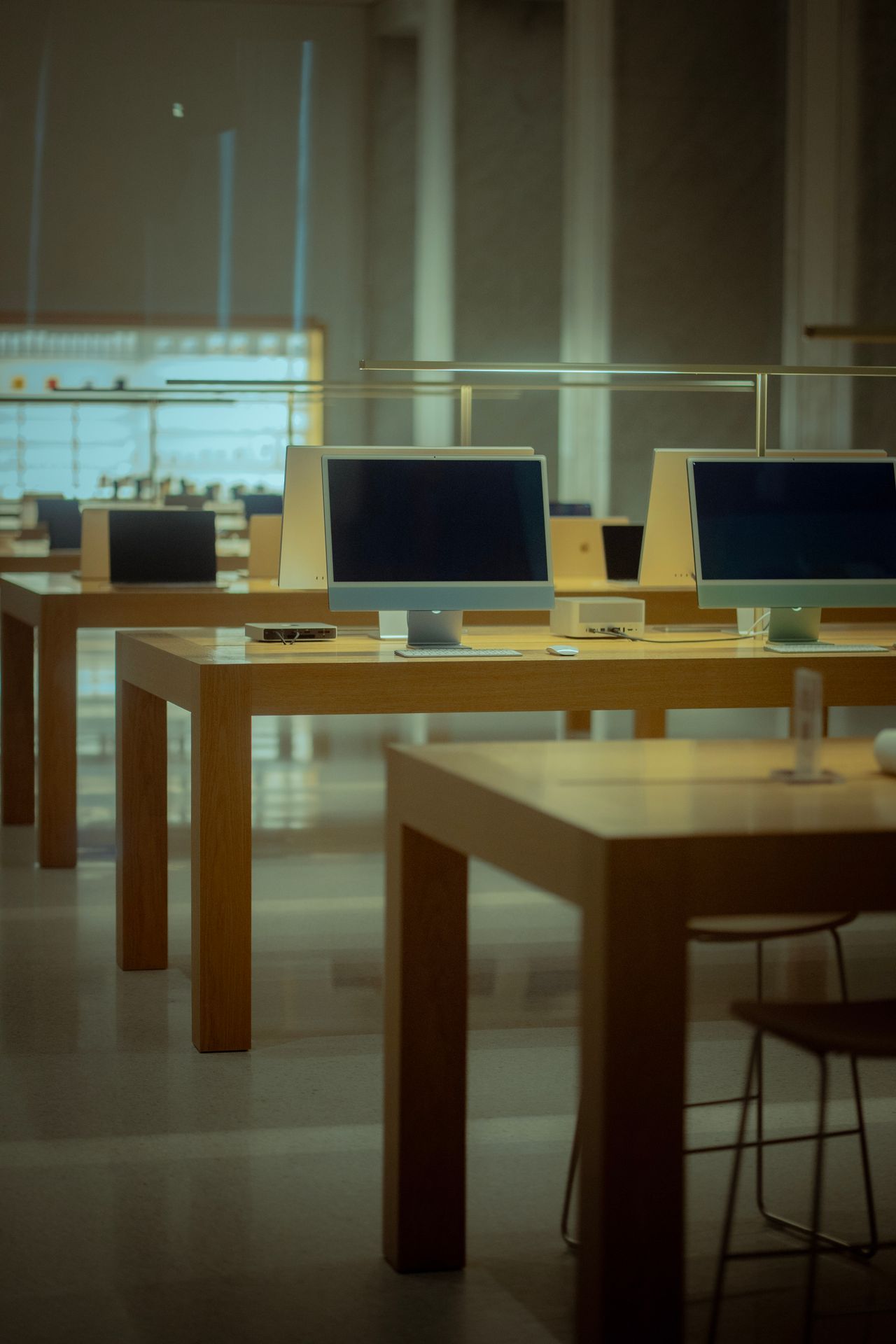 Empty computer store with wooden tables and modern desktop computers displayed.