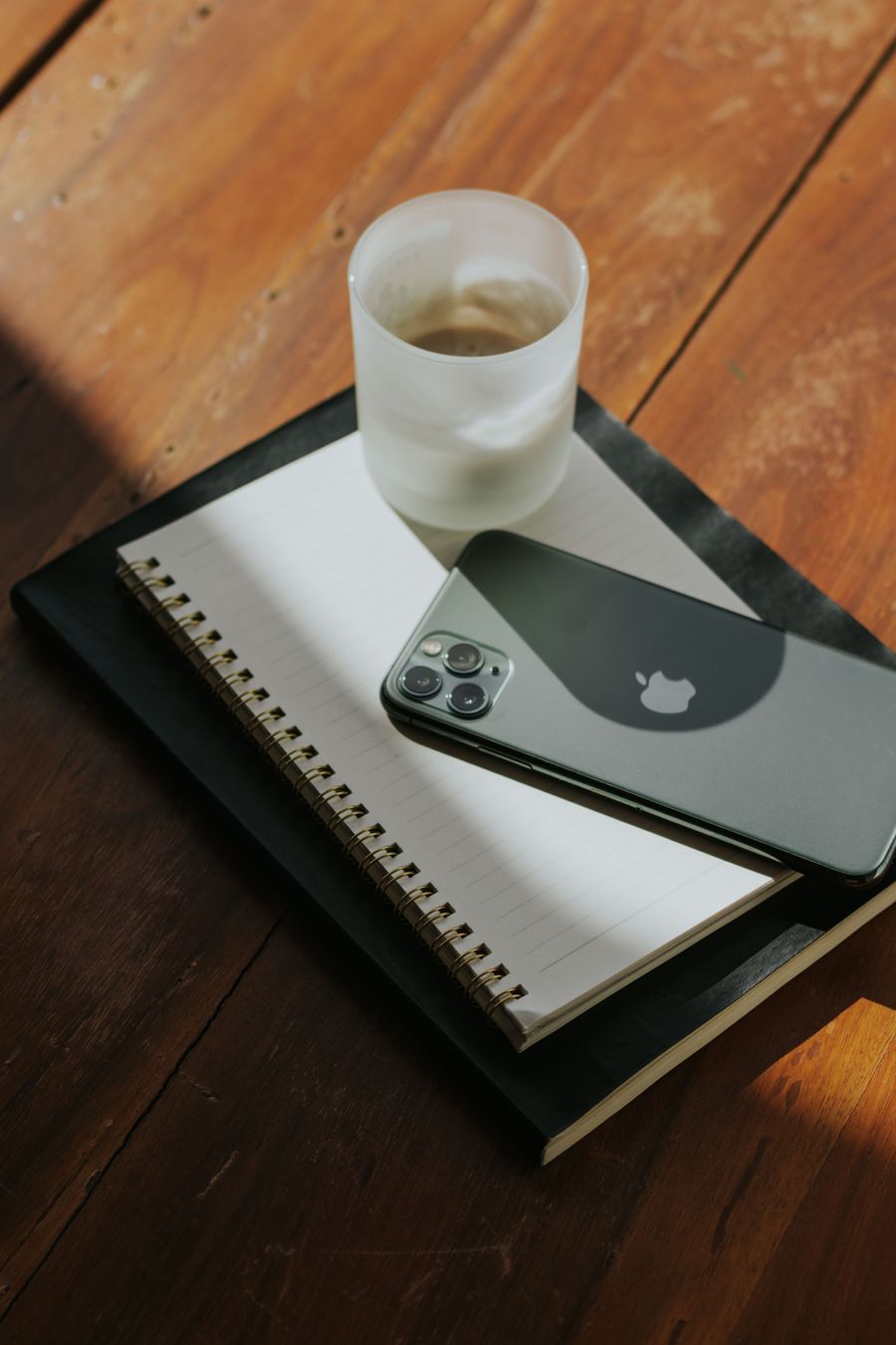 Celular e caderno organizados sobre uma mesa
