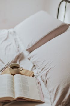 Warm morning setting with coffee and book on bed, perfect for relaxation.
