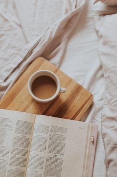 Cozy morning scene with open book and coffee on bed, perfect for relaxation.