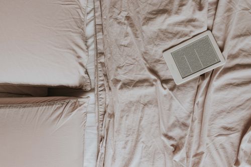 Free Top view of a cozy bed with an ebook reader on soft sheets, perfect for relaxed reading enthusiasts. Stock Photo