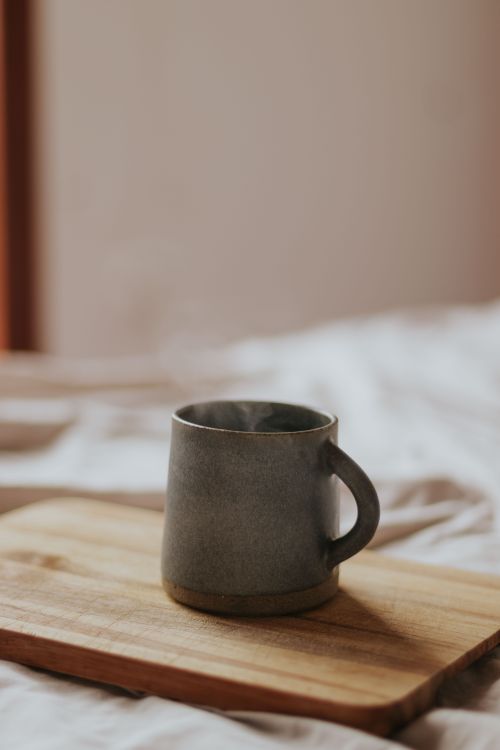 Free Grey ceramic mug placed on wooden board with cozy ambiance. Stock Photo