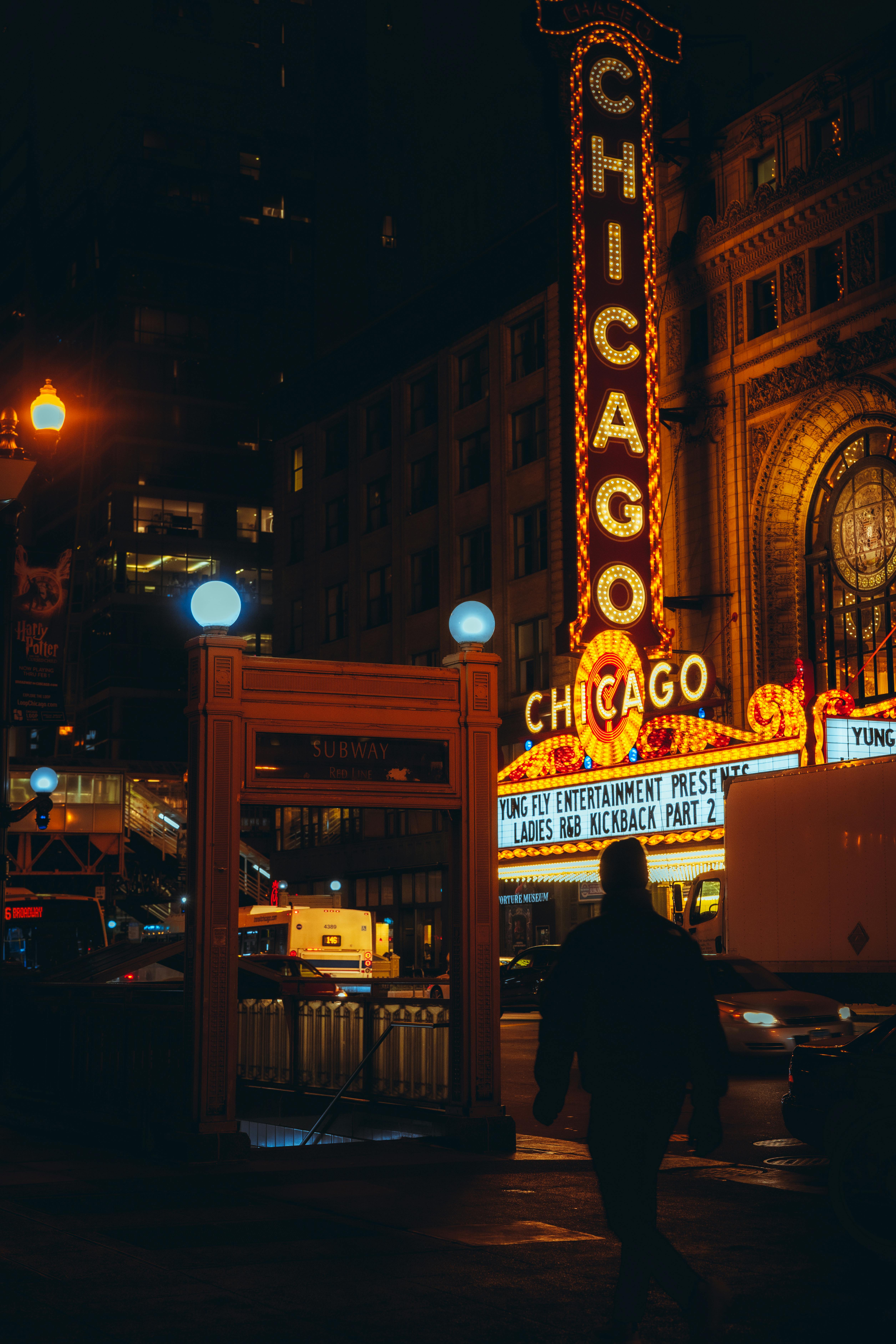 Ücretsiz Chicago'nun ikonik tiyatro tabelası ve şehir ışıklarıyla canlı gece manzarası. Stok Fotoğraflar