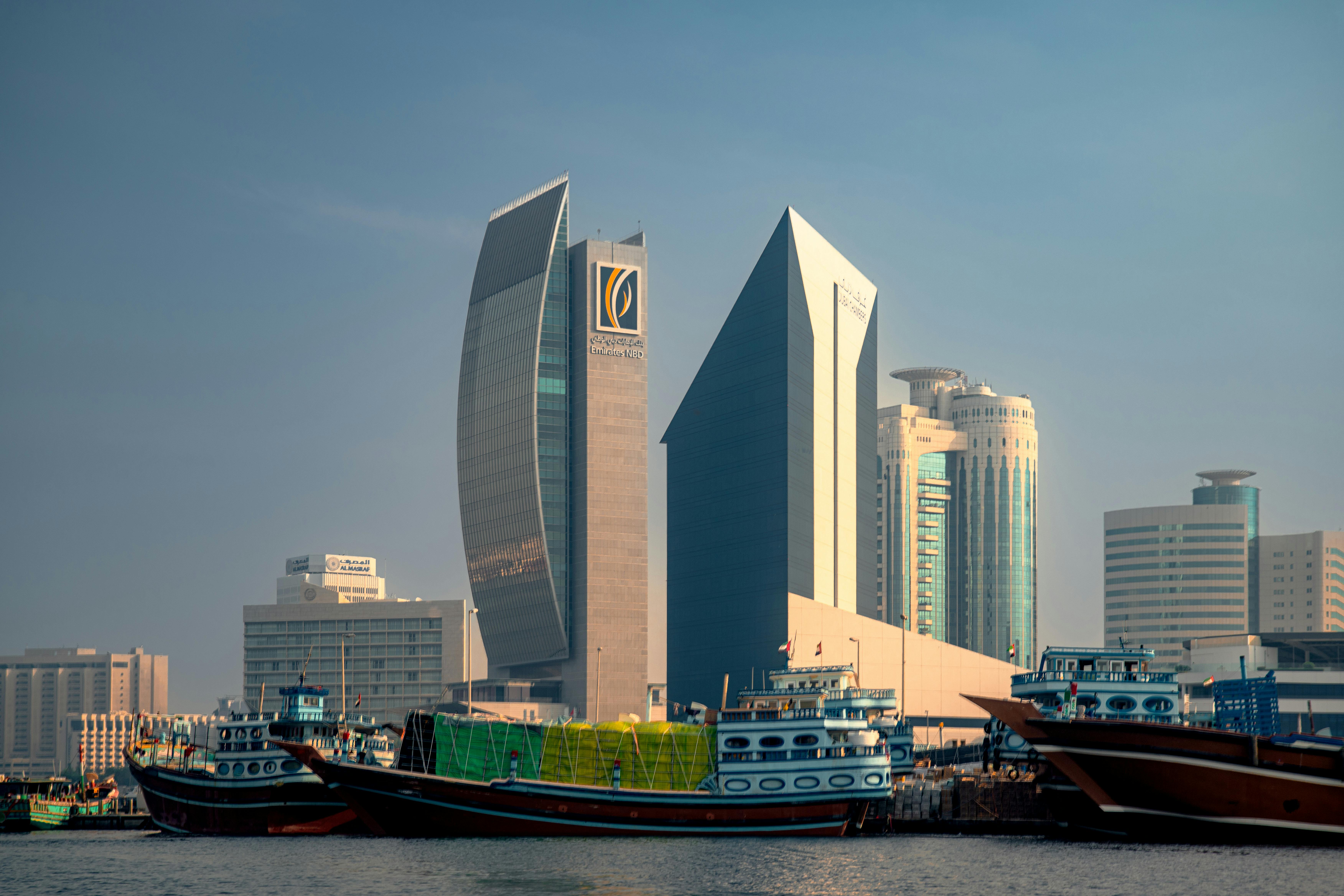 A stunning view of modern skyscrapers contrasted with traditional boats in Dubai's waterways.