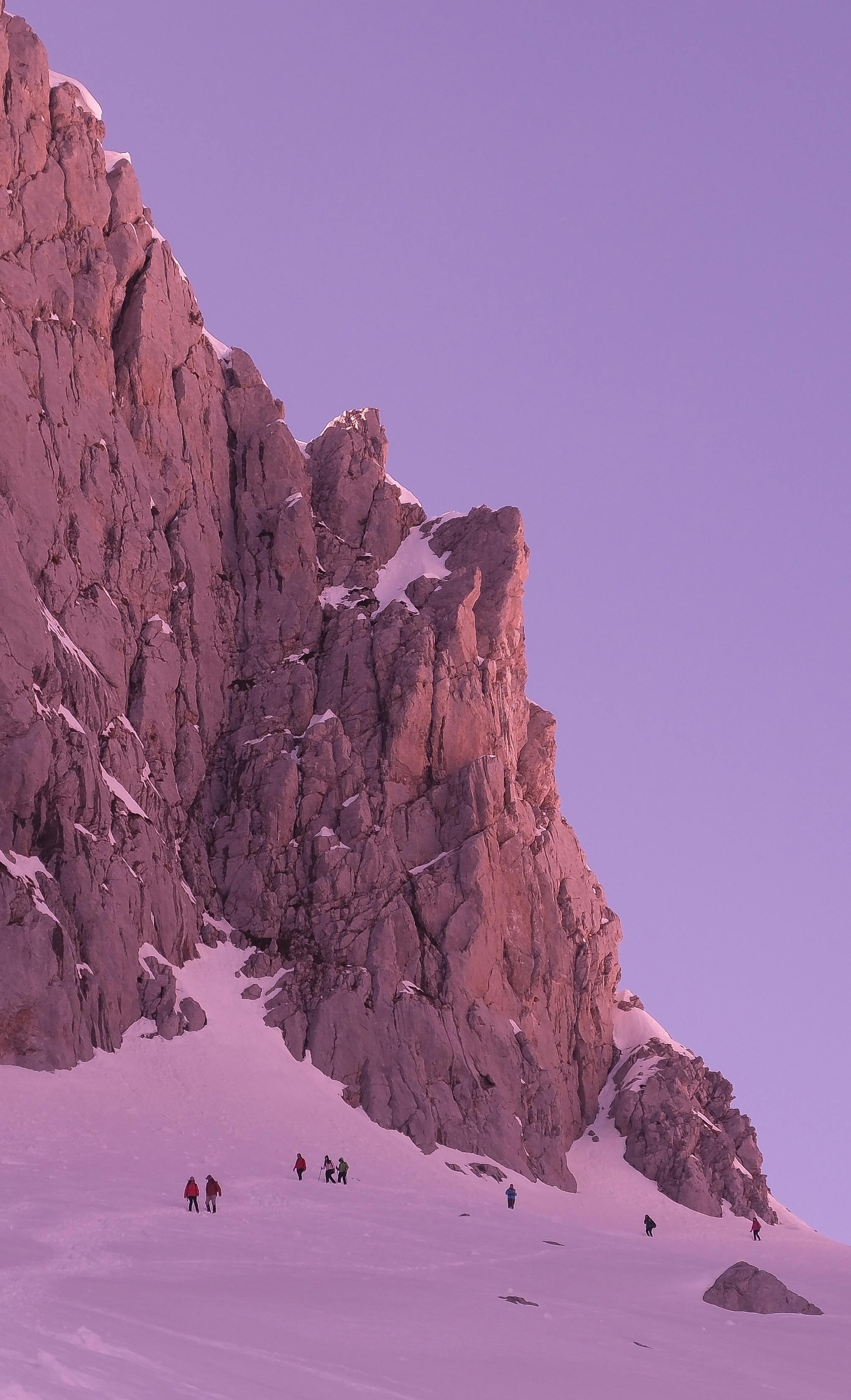 Climbers ascend a snowy peak in Shkodër County, Albania at dusk.