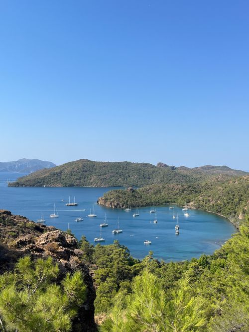 Free A breathtaking aerial view of a serene coastal bay dotted with sailboats and lush green hills. Stock Photo