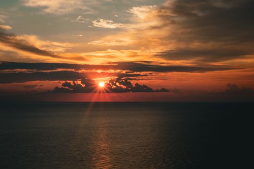 Free A breathtaking sunset casting vibrant warm hues over a serene ocean view. Stock Photo
