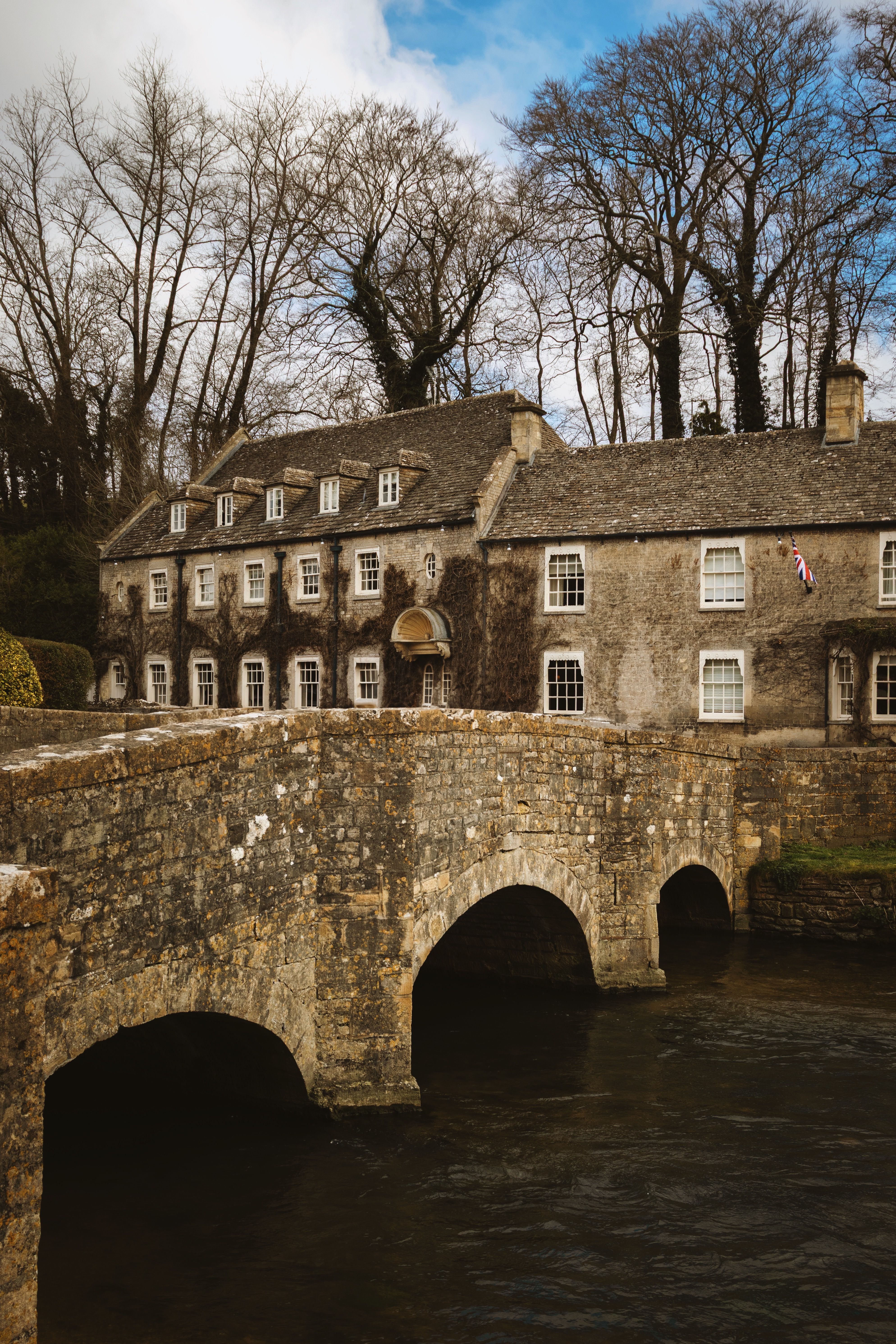 Honey-stone cottages beside a low bridge over the river in Bourton-on-the-Water in the Cotswolds