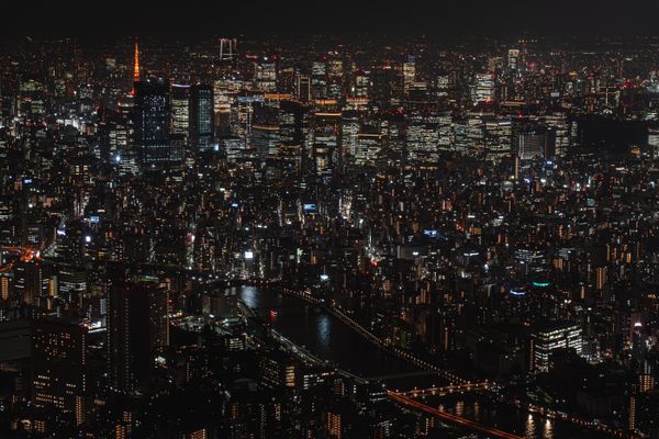 Uma vista aérea fascinante da paisagem urbana iluminada de Tóquio à noite, destacando a vibrante vida urbana.