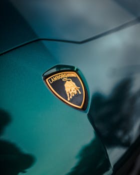 Detailed view of Lamborghini emblem on a sleek green sports car hood.