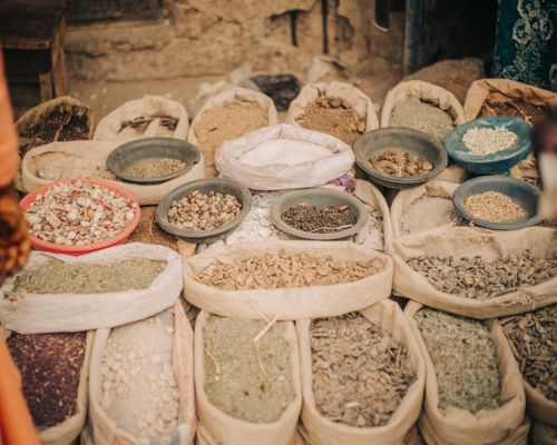 Free Bags and bowls filled with diverse dried herbs and spices displayed at an outdoor market. Stock Photo