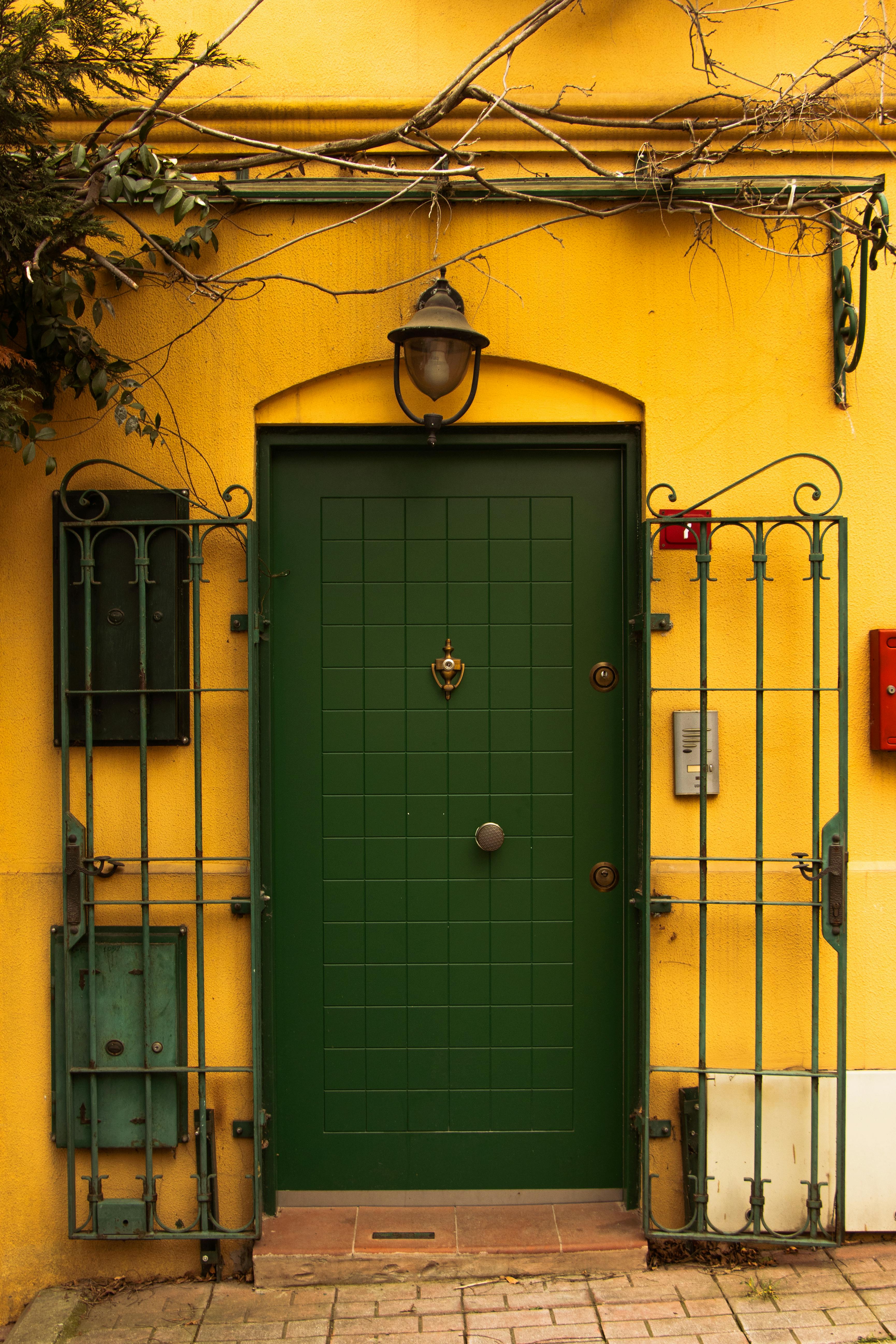 Rustic green door with intricate metalwork set against a vibrant yellow wall in İstanbul, Türkiye.