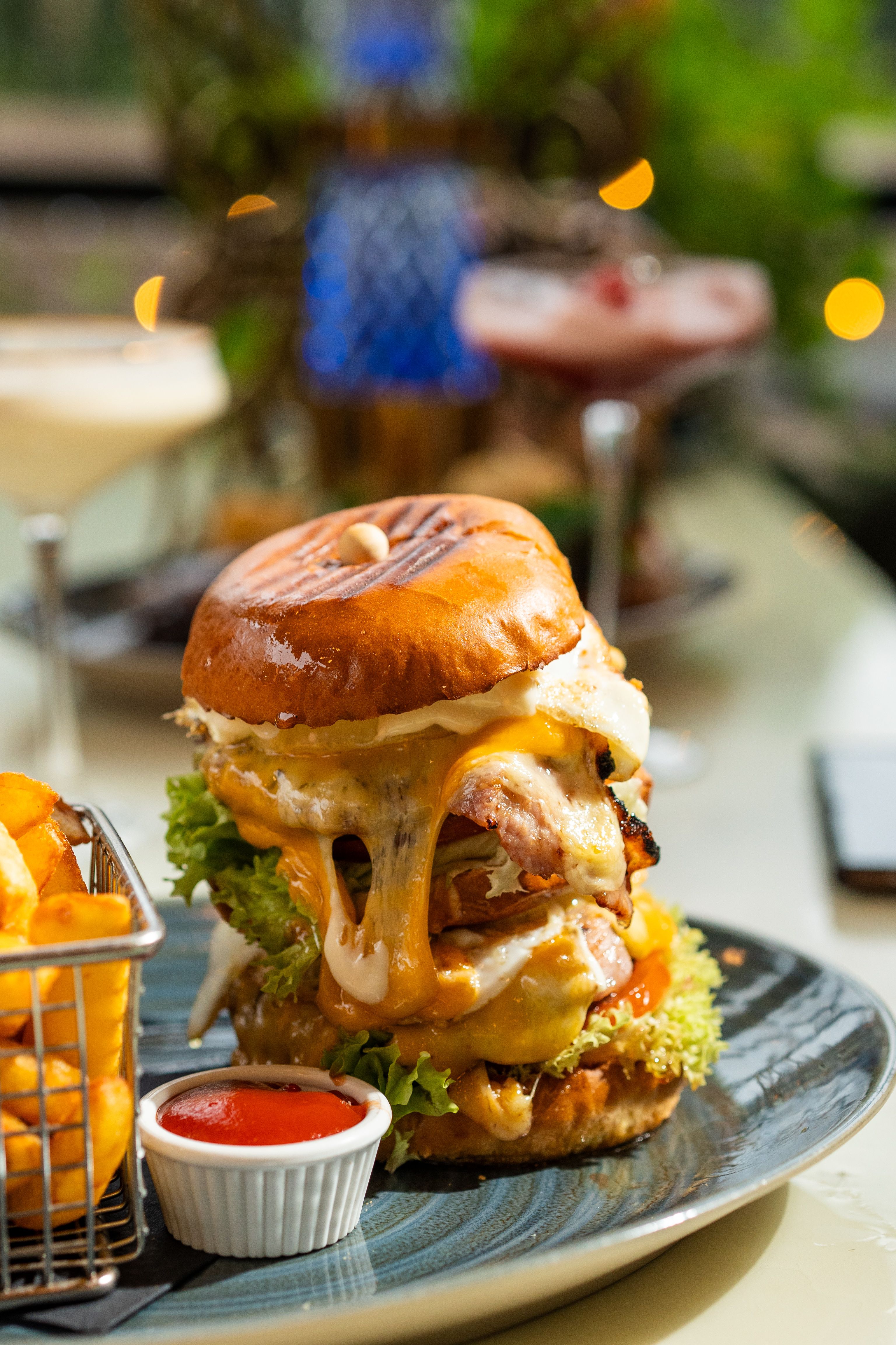 Mouthwatering gourmet burger with melted cheese and fries in a lively setting.