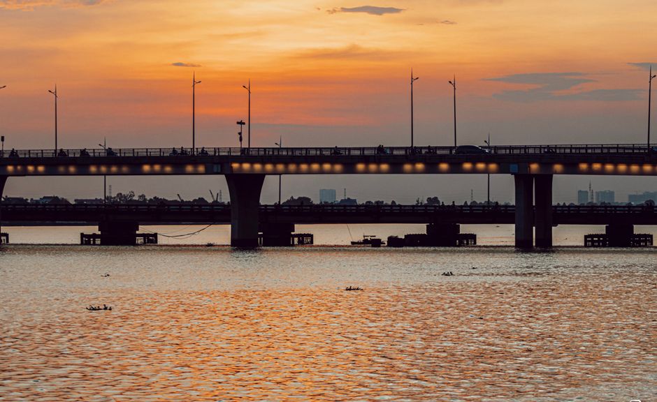 Serene view of a bridge at sunset with calm waters reflecting the vibrant sky.