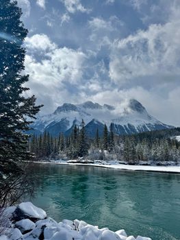 A stunning winter view of Canmore with snow-covered mountains and a tranquil river.