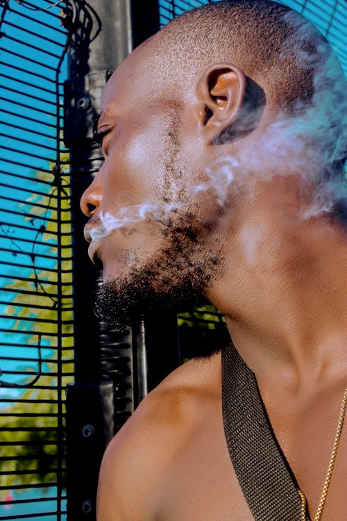 Free Close-up of a man exhaling smoke with a vibrant background, capturing the essence of outdoor lifestyle. Stock Photo