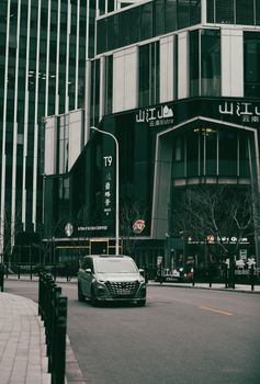 City street scene featuring modern architecture and a car on a quiet road.