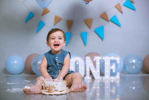 Happy baby enjoying a first birthday cake smash with colorful decorations.