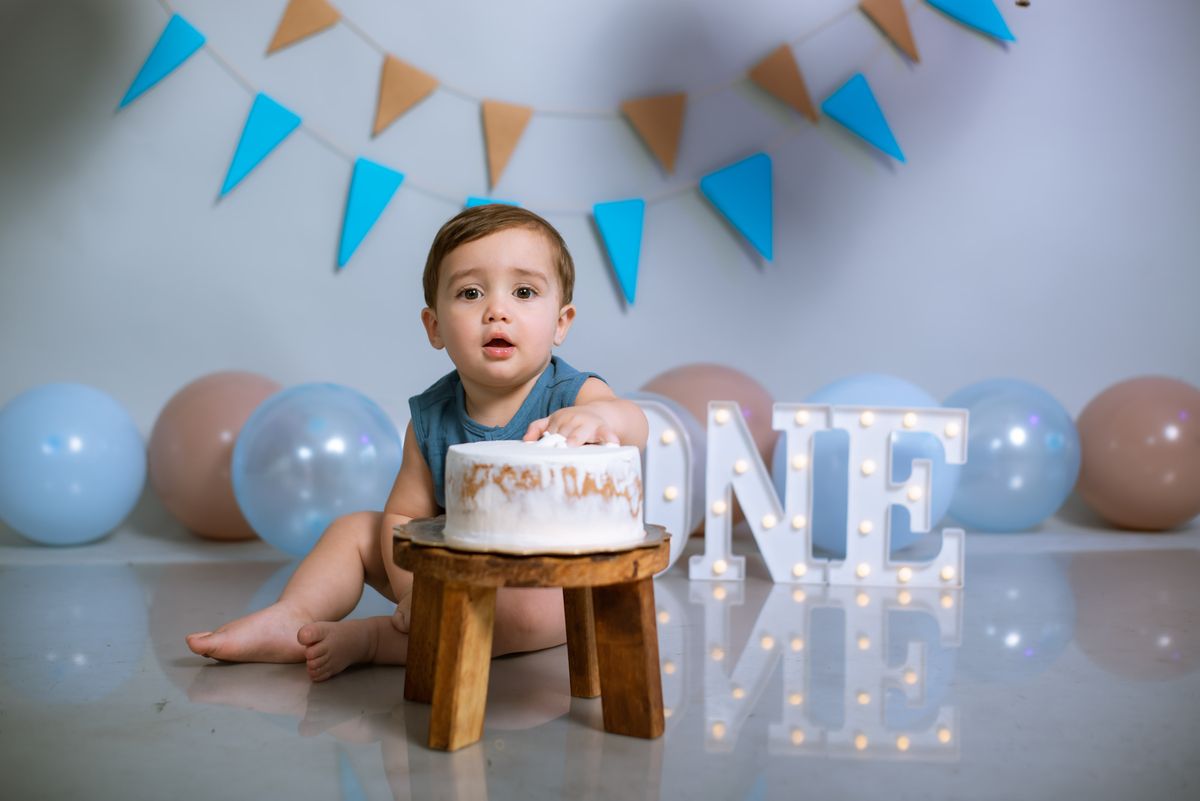 First birthday smash cake photo with a baby and balloons