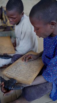 Two children engaged in reading an ancient manuscript, focused and curious.