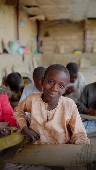 Young African boy smiling in a classroom, representing education and joy.