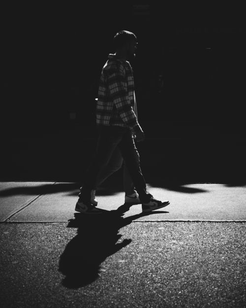 Free Black and white silhouette of a person walking on a city street at night. Stock Photo