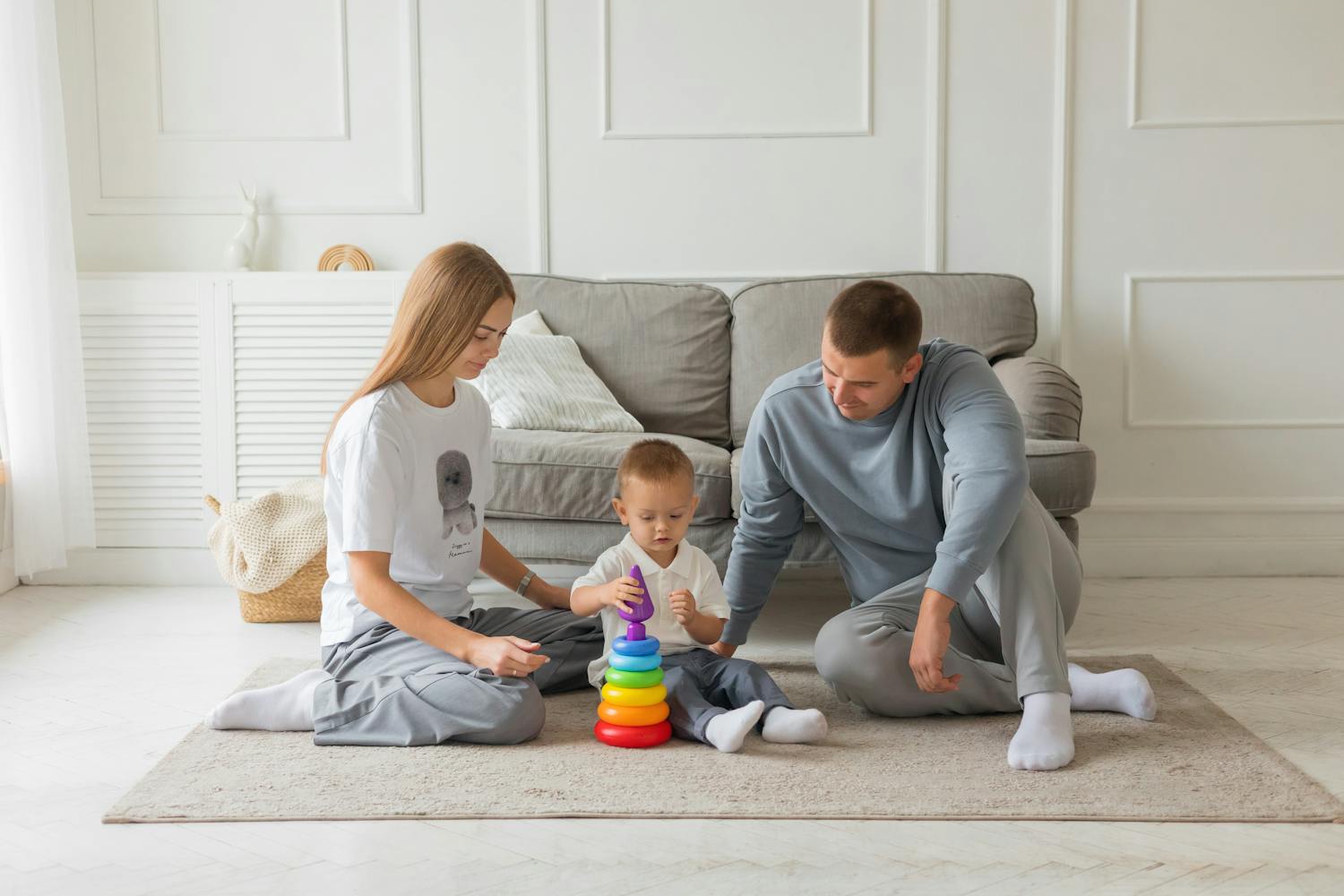 Mom, dad, and young child playing with colorful stacking toy