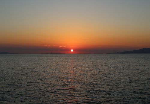 Free Peaceful sunset over the ocean with calm waters and vibrant sky colors. Stock Photo