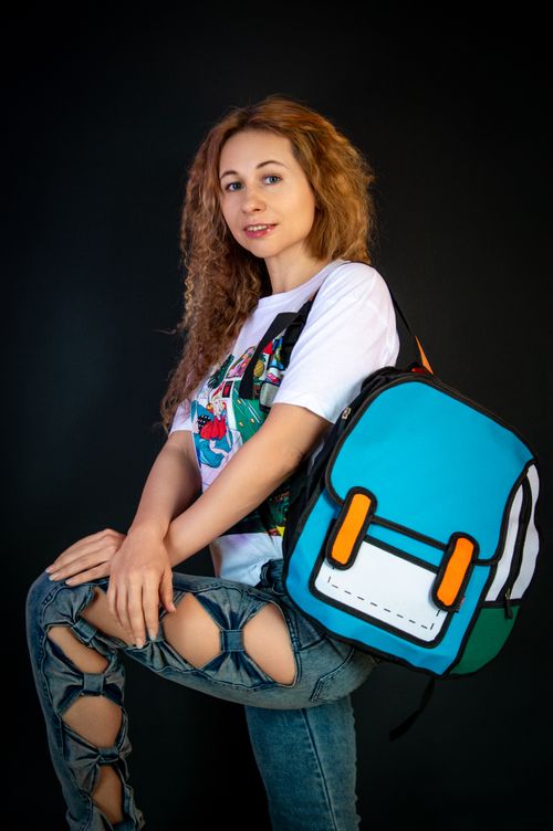 Free Stylish young woman poses with a unique cartoon style backpack and ripped jeans. Stock Photo