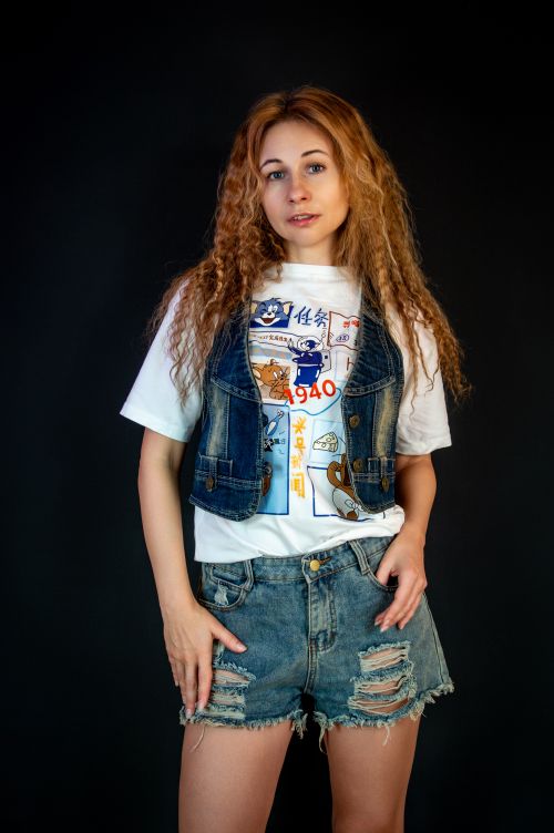 Free Casual style portrait of a young woman wearing a denim vest and ripped shorts. Stock Photo